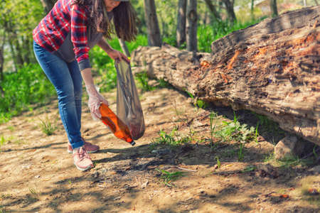Woman volunteer helps clean the forest of plastic garbage. Earth day and environmental improvement concept.の写真素材