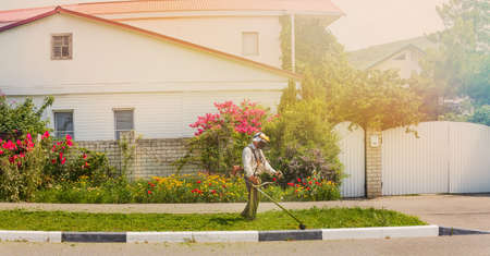 the gardener finishes mowing the lawn trimmer on the background of the house.の写真素材