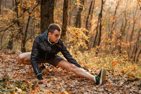 Concept of sport and active lifestyle. A young man is engaged in warm-up, fitness in the autumn...
