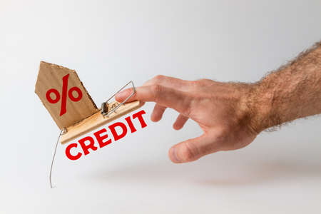 Concept of Bank investments and risks. A man's hand falls into a mousetrap, with a cardboard insert...