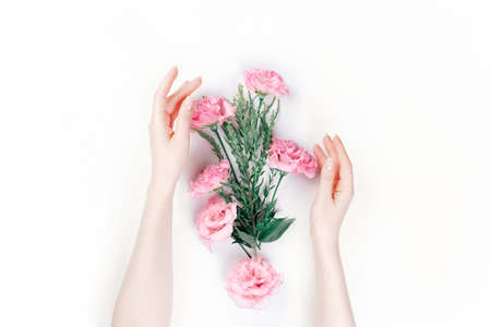 Delicate female hands frame the scattered pink buds of eustoma. White background. The skin is albino. Flat lay. The concept of Floristics and tendernessの写真素材