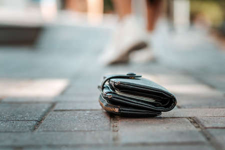 On the ground is a lost leather skin. In the background, the legs of the departing man are blurred. The concept of loss.の写真素材