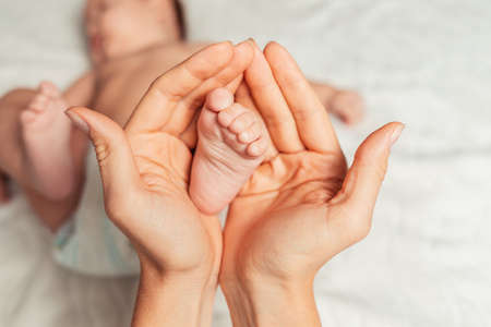 A mother holds the baby's foot in her palms.