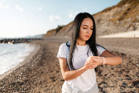 Sport. Young beautiful woman looks at her pocket watch while Jogging.の写真素材