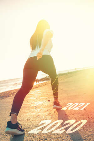 The concept of a calendar and change the year. A woman in sportswear runs from 2020 to 2021. Rear...