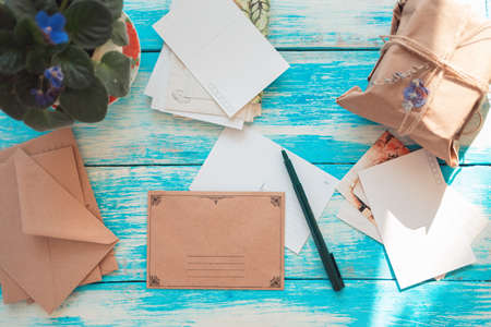 Vintage composition of postcards, pen, envelopes, and parcel. Blue wooden background. Flat lay. Copy space. The concept of mail and postcrossing.の写真素材