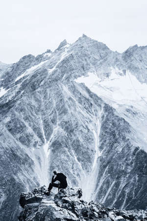 Hiking and climbing. Tourist posing on top of a mountain ledge. Monochrome.の写真素材
