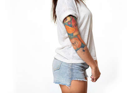 A woman in casual clothes, with a tattoo on the hand, standing on a white background. Side view. Close up.の写真素材