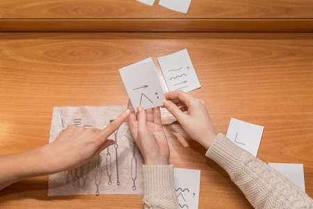 the doctor points to the sound card. hands on the table holding exercise cards for the sounds of...