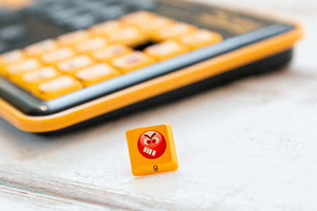 Button with an angry emoticon on the keyboard background. Close up. Copy space. Concept of social...