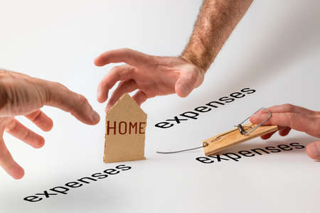 Concept of Bank investments and risks. Three men's hands are drawn to the cardboard character of the house. Text EXPENSES.の写真素材