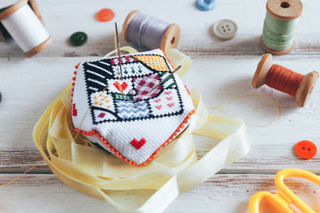 Handmade and needlework. Handmade pin cushion with a simple ornament and sewing supplies on the...