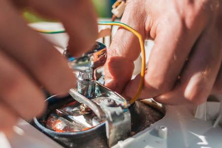 Repair and maintenance of the water heater. The man fixing detail of the boiler. Hands close up.