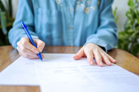 World leasing day. A woman signs documents. Hands close-up. Indoor.
