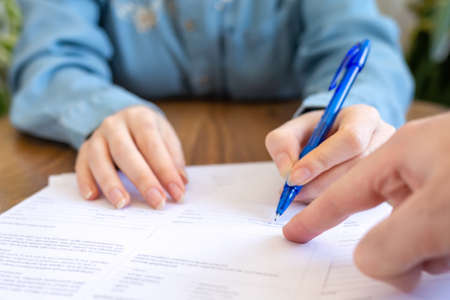 World leasing day. The employee points his finger at the contract where you need to sign it. Hands close-up. Rental and purchase of real estate.の写真素材