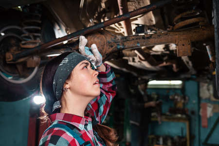 Portrait of a young woman mechanic conducting an inspection of the car body. Side view.の写真素材