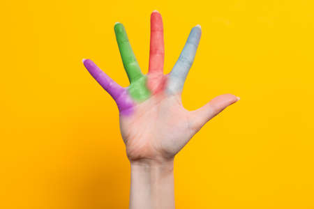A woman's hand with multicolored fingers spread out. Yellow background. The concept of the world day of protection of children.の写真素材