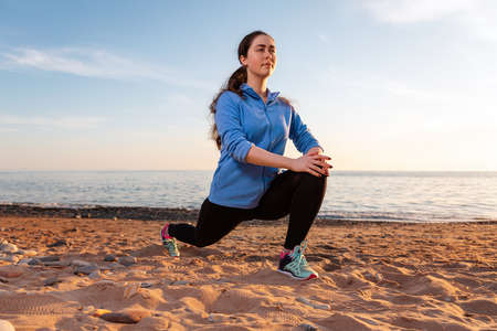 A young woman plays sports on the sandy beach of the ocean. Outdoor. Sports and healthy lifestyle.