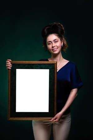 A young smiling caucasian woman holds a frame with a white space. Mock up. Copy space.の写真素材