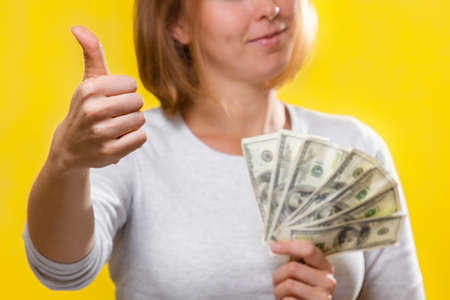 Finance, loans and banking. Close up of a young blonde holds a wad of dollars in her hands and gives...