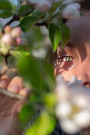 Close-up portrait. A beautiful woman holds a sprig of flowers, covering her face.