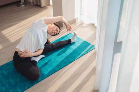 A young pretty woman in sportswear doing yoga on the sports mat. Indoors. The concept of sports at...