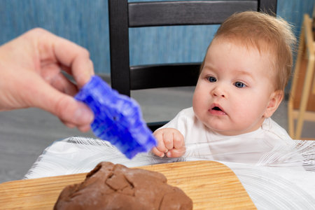 Mother shows a small child a cookie cutter. Close-up portrait of the baby. The concept of home cooking and cooking together with children.の写真素材