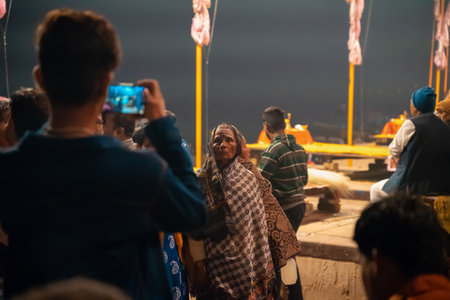12/17/2019, Varanasi, India. A man takes a video of an old Indian woman. Night festival.のeditorial素材