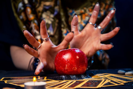 A fortune teller conjures a red apple lying on the Tarot cards. Close up. The concept of divination, astrology and esotericism.の写真素材