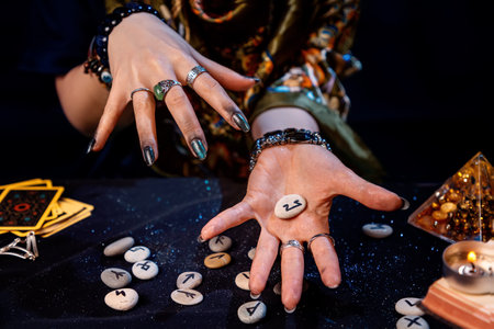 The fortune teller holds a rune in the palm of her hand. Top view. The concept of divination, astrology and predicting the future.の写真素材