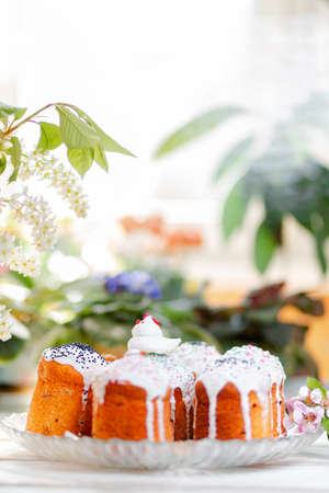 Group of decorated Easter cakes on a platter with apple blossom and branch of cherry. In the background-plants and flowers. Vertical orientation. Easter holiday. Copy space.の写真素材