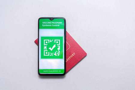 Electronic Immunity passport with a COVID-19 vaccination stamp on a smartphone screen with passport on the world map. Flat lay. Medicine and health concept. Copy space.の写真素材