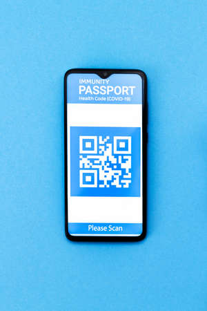 Electronic Immunity passport with a COVID-19 vaccination stamp on a smartphone screen. Blue background. Flat lay. Medicine and health concept. Vertical.の写真素材