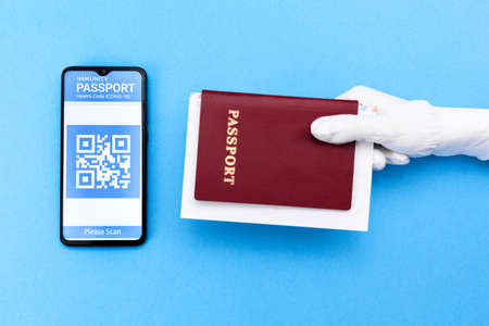 A hand in glove holds a passport. Cellphone screen with an electronic health passport with qr-code. Flat lay. Concept of Covid-19 test for travel.の写真素材