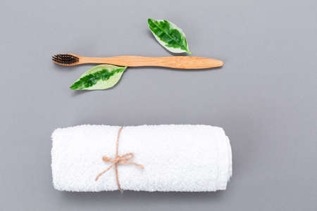 A roll of white towel and a bamboo toothbrush. Flat lay. Gray background. Top view. The concept of eco-friendly hygiene products.の写真素材