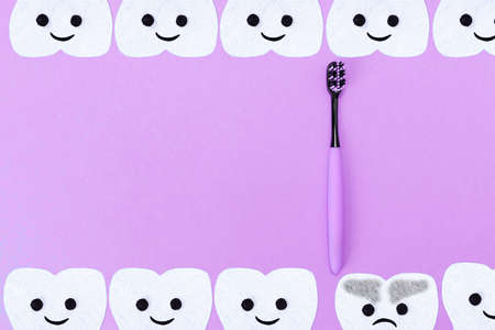 Concept of tooth care. A plastic toothbrush and cartoon teeth cut out of felt on a blue background. Flat lay. Copy space.の写真素材