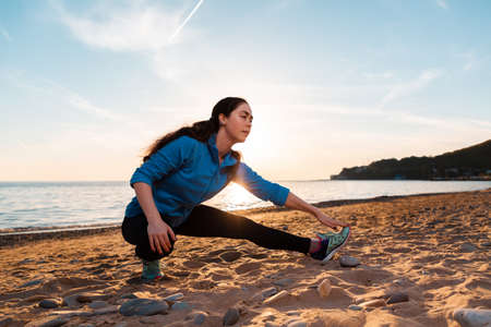 A young caucasian woman is playing sports on the sandy beach of the ocean. Outdoor. Sports and healthy lifestyle.の写真素材