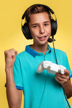 The concept of virtual and computer games. A teenage boy in a blue t-shirt and headphones, with a...