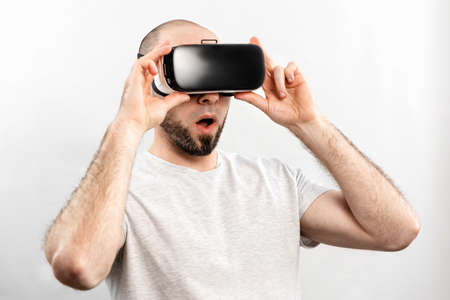 The concept of virtual reality. Portrait of a surprised adult man in virtual reality glasses, with...