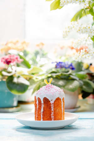 One decorated Easter bread on a plate. In the background-plants and flowers. Vertical orientation....