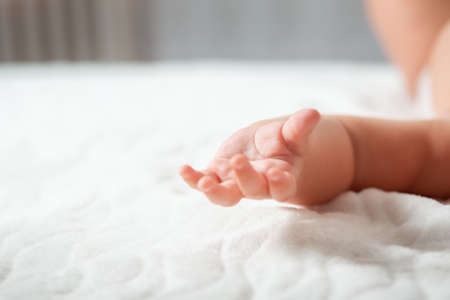 Mother's Day concept. Baby's hand close-up, on a white sheet.