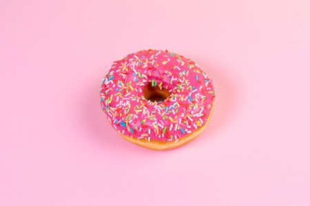 Round donut with pink icing close up. Pink background. Copy space. Flat lay.の写真素材