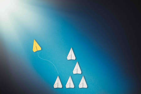 The concept of individuality and freedom. A yellow paper airplane takes off from a group of white...