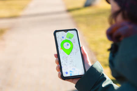 A woman holds a cellphone with the online maps app open and looks at the marked location. Close up...