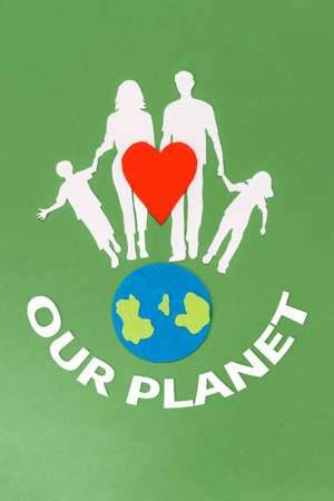 Earth Day. A felt-cut symbol of the planet earth and a red heart with paper silhouette of family. Green background with text. Flat lay. Vertical. The concept of environmental protection.の写真素材