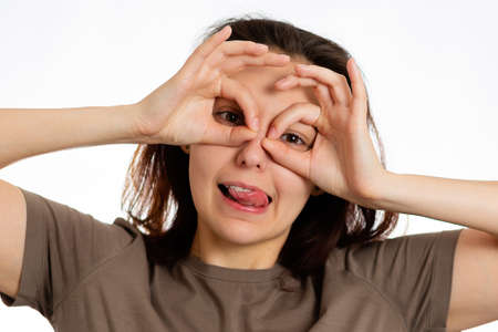 Portrait of a young Caucasian woman makes a grimace. White background. The concept of April Fools'...