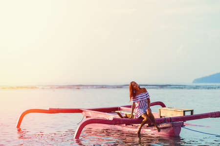 tanned girl with a smile at sunset in the sea on a boat.against the sky and the sea. in soft focus.
