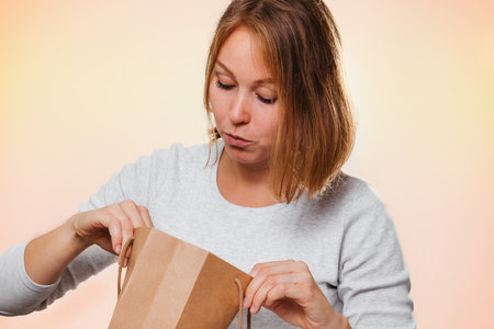 Portrait of a woman looking into a shopping bag. The concept of shopping and consumerism.の写真素材