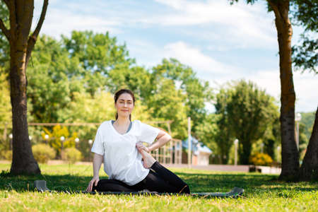 Yoga. A young woman in sports clothes, doing an exercise in the Park on the grass. Copy space. The...