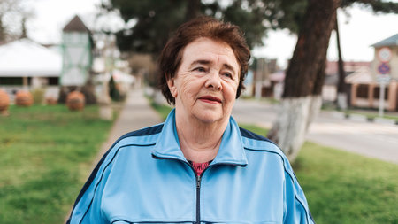Close up portrait of an elderly smiling woman in a tracksuit. Outdoor. Concept of International Day...